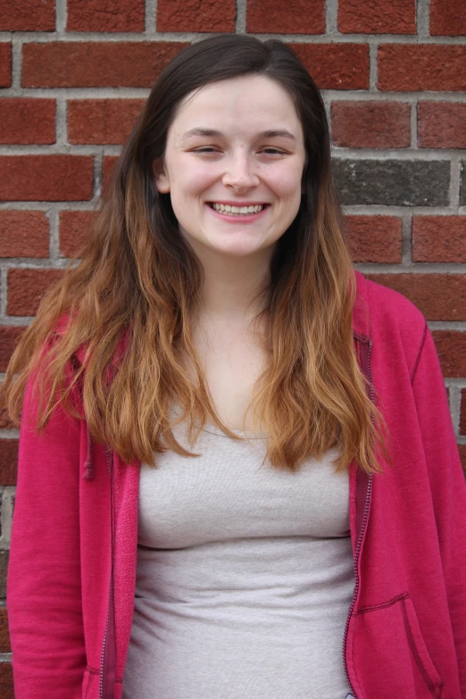 a woman is standing next to a brick wall