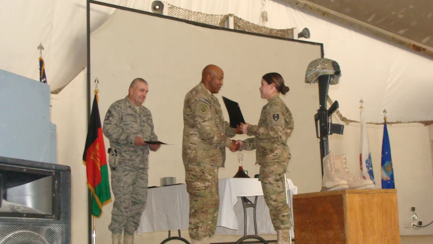 three people in uniform and one man is shaking hands