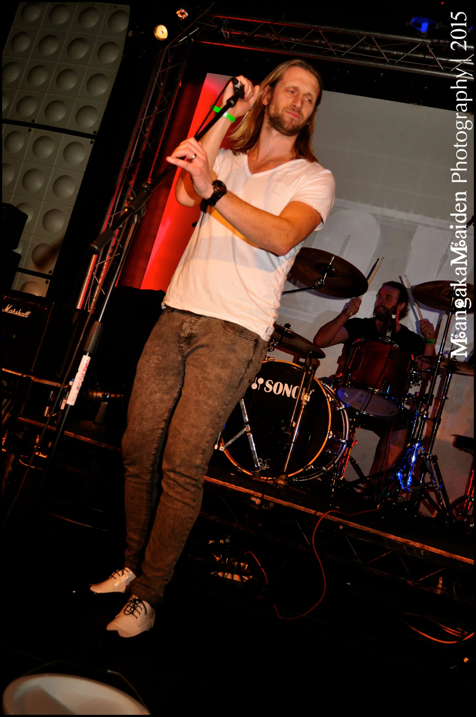 the man with long hair and glasses is performing on stage