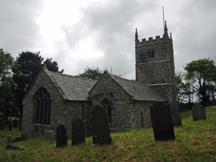 a graveyard with old - fashioned tombstones with a church steeple behind it