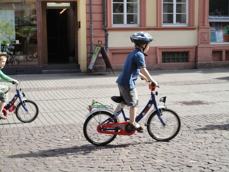 two young children are riding their bikes on the sidewalk