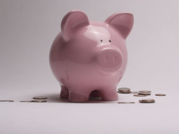 a pink pig sitting on top of a pile of coins