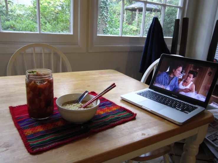 a bowl with rice on it sits next to a laptop computer with a couple kissing