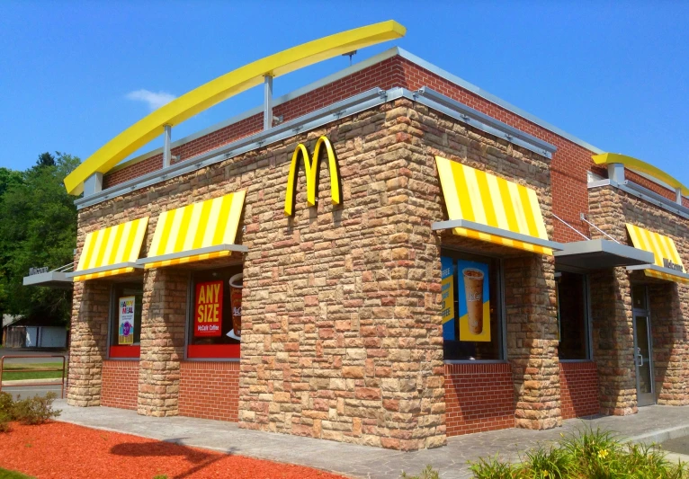 a small brick building with a yellow roof and mcdonald's sign