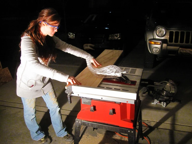 a girl is making soing on a table saw