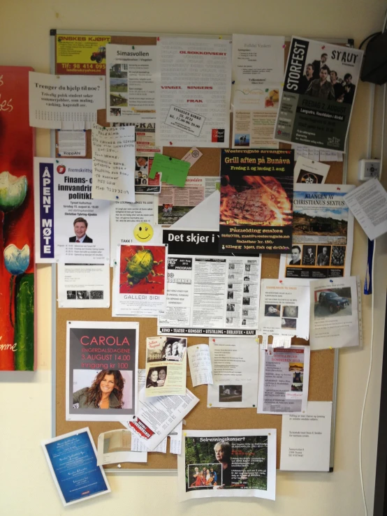 a bulletin board with papers, pictures and magnets pinned to it