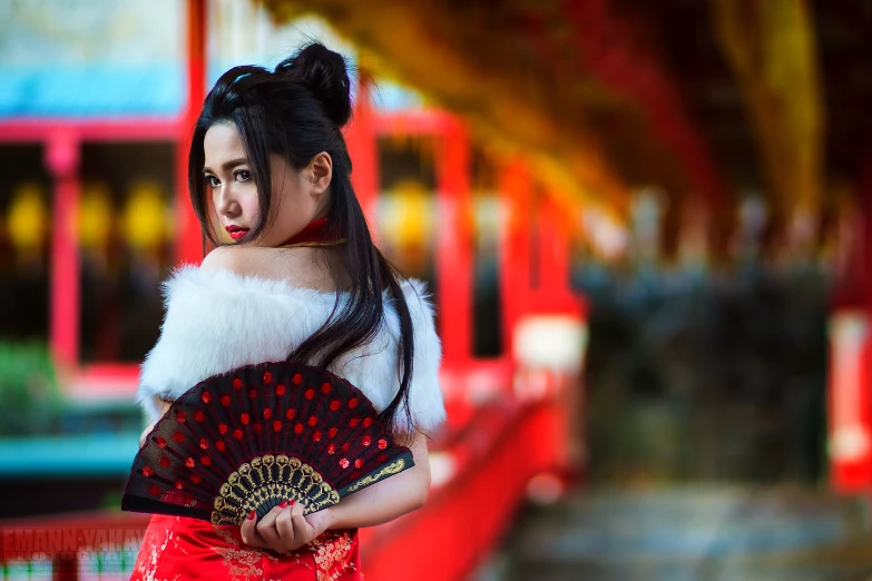 a  in a chinese dress holding a red fan