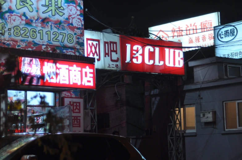 several neon signs hang above the city streets