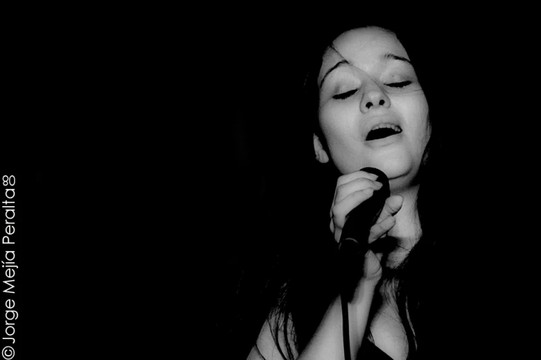 black and white pograph of woman singing into a microphone