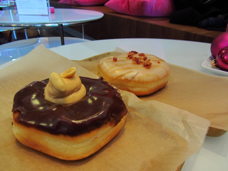 two donuts sit on a piece of paper sitting on a table