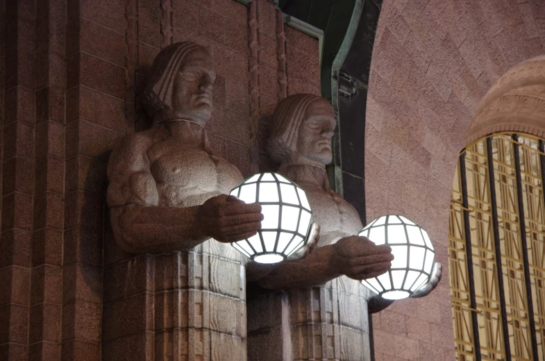 two stone statues holding globes in front of a window