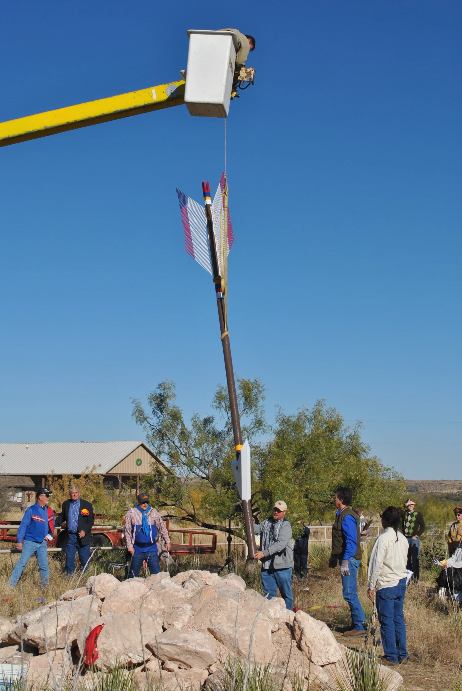 a large crane lifts a group of people from the desert