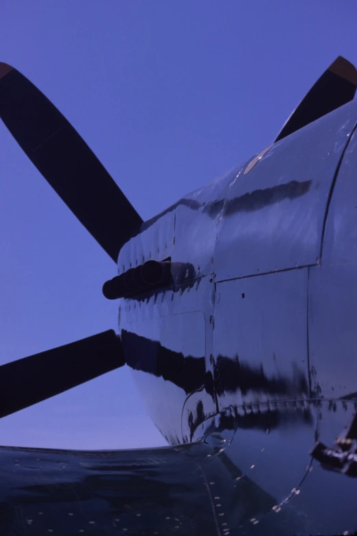 the nose of a propeller airplane is seen at dusk