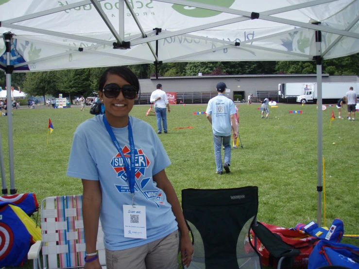 a smiling woman in a blue shirt stands under a tent