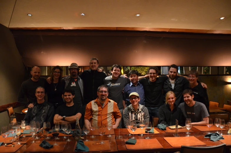 group of people standing around a table with wine glasses on top of it