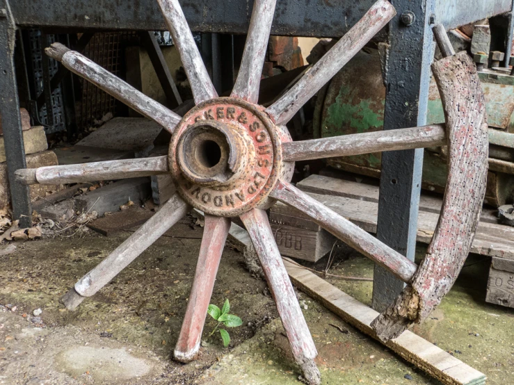 an old wheel with rusty paint sitting in a junk yard