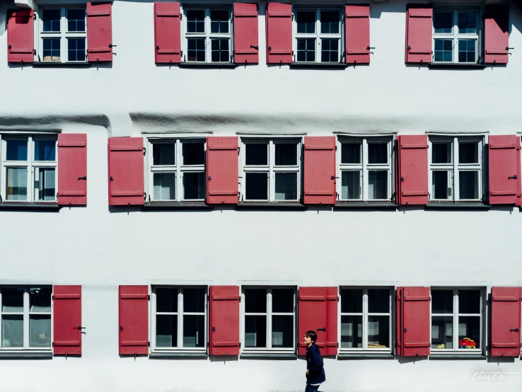 a man is walking on a sidewalk near several windows