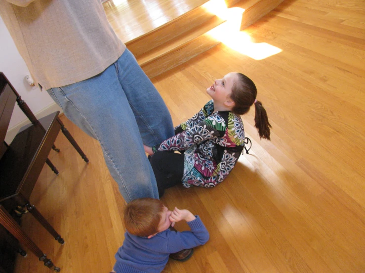 two young children standing and playing on the floor with their dad