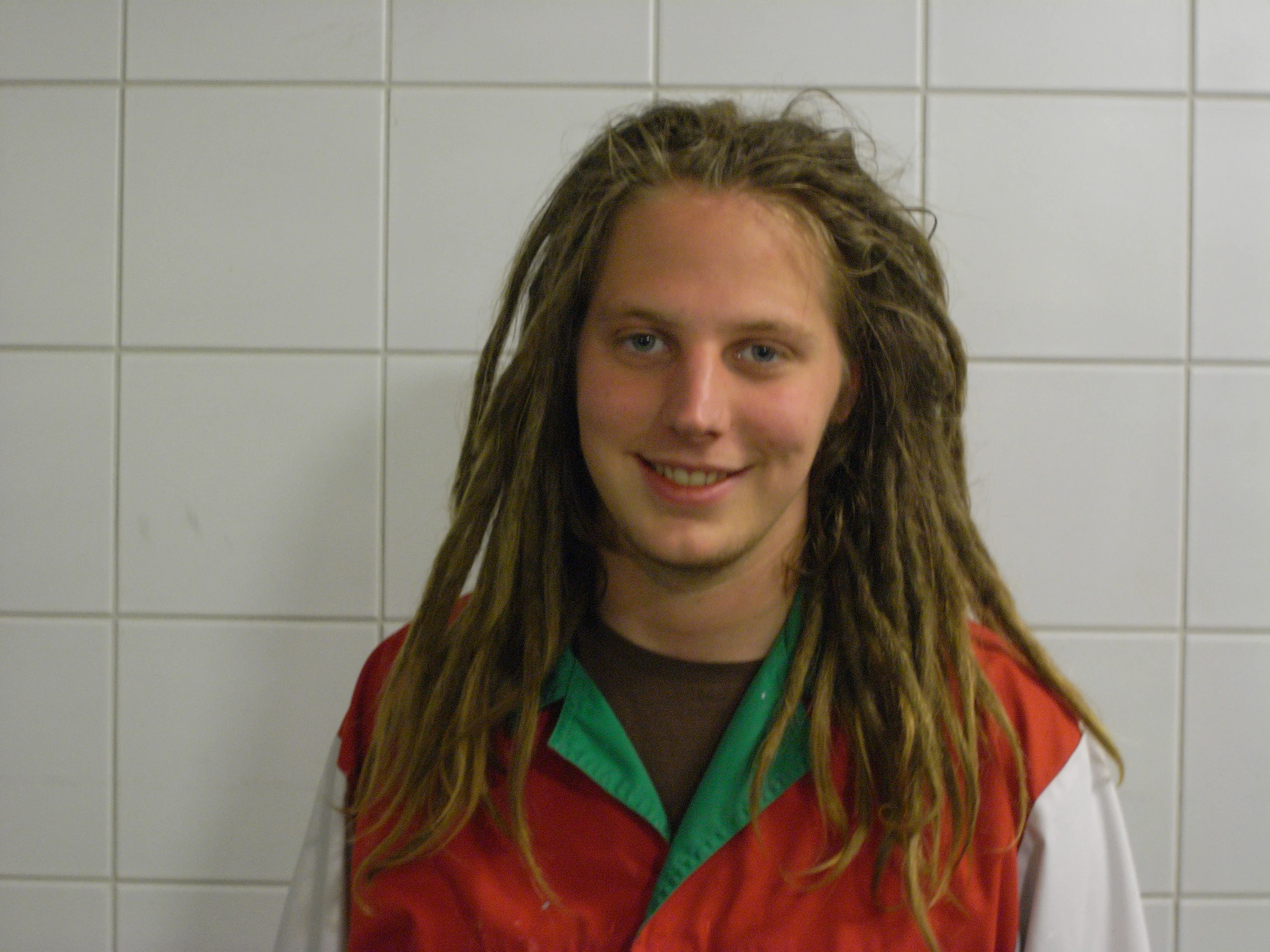 a young man with dreadlocks standing in a restroom