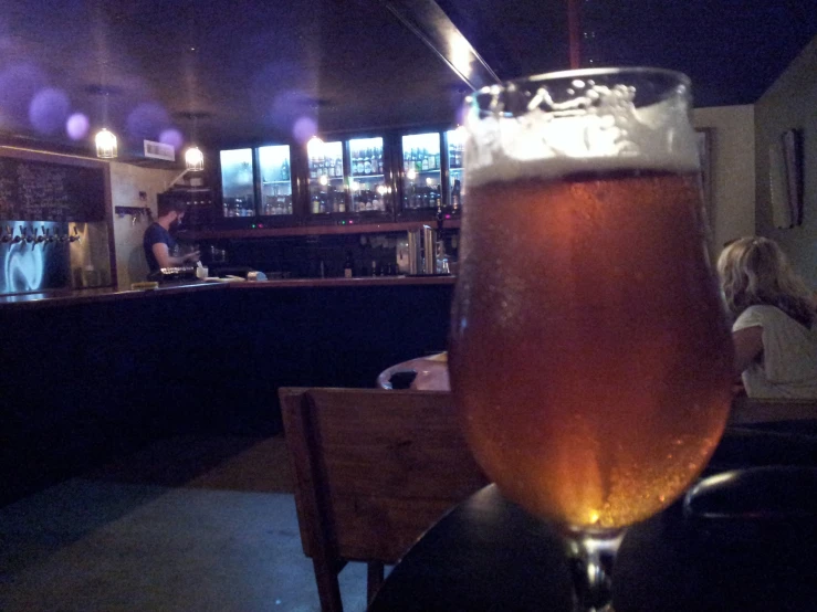 a tall glass with liquid next to an empty bottle