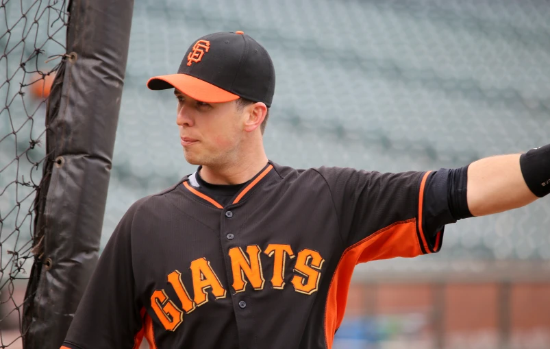 a man in an giants uniform is standing near a baseball net