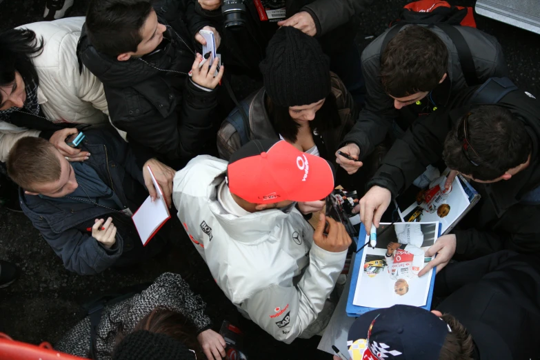 many people standing around and one is using his cell phone