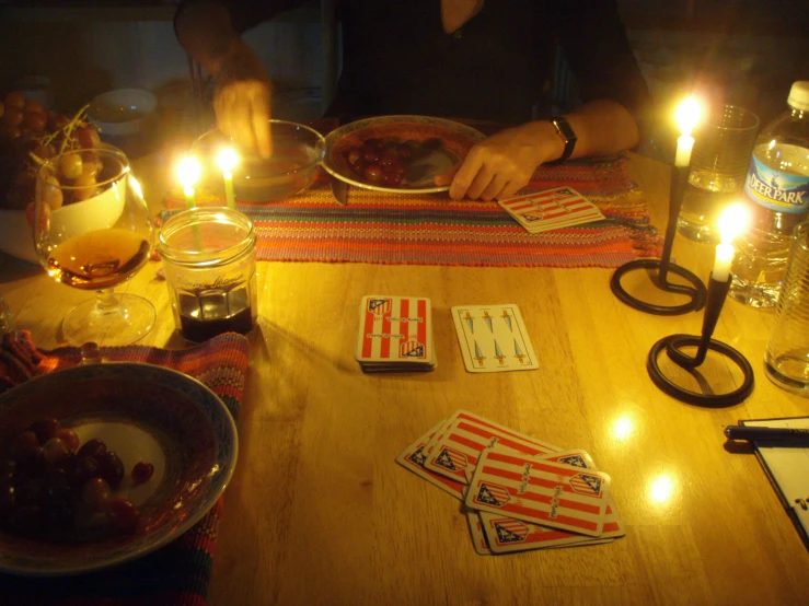 a person sitting at a table with playing cards and drinking wine