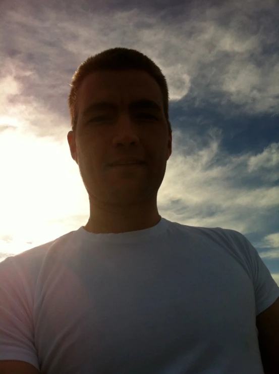 a guy in white shirt taking a selfie in front of blue sky