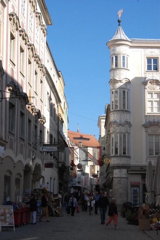 a group of people walking on a narrow street in front of tall buildings