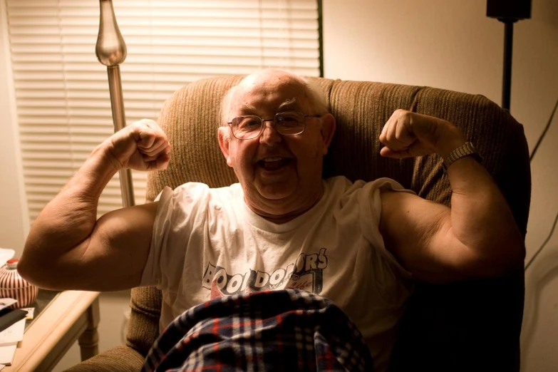 an old man flexing his muscles in a chair