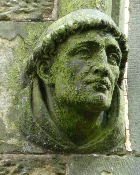 an old statue head on the outside wall of a building