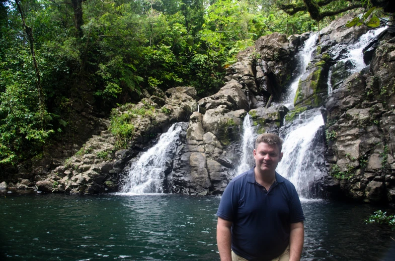 man standing in front of waterfall with pool