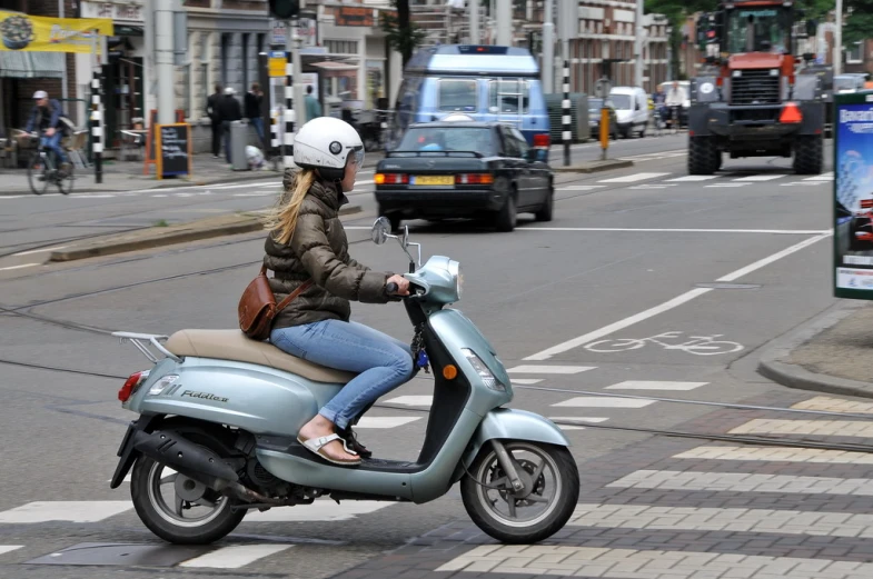 the woman in jeans and heels rides a scooter