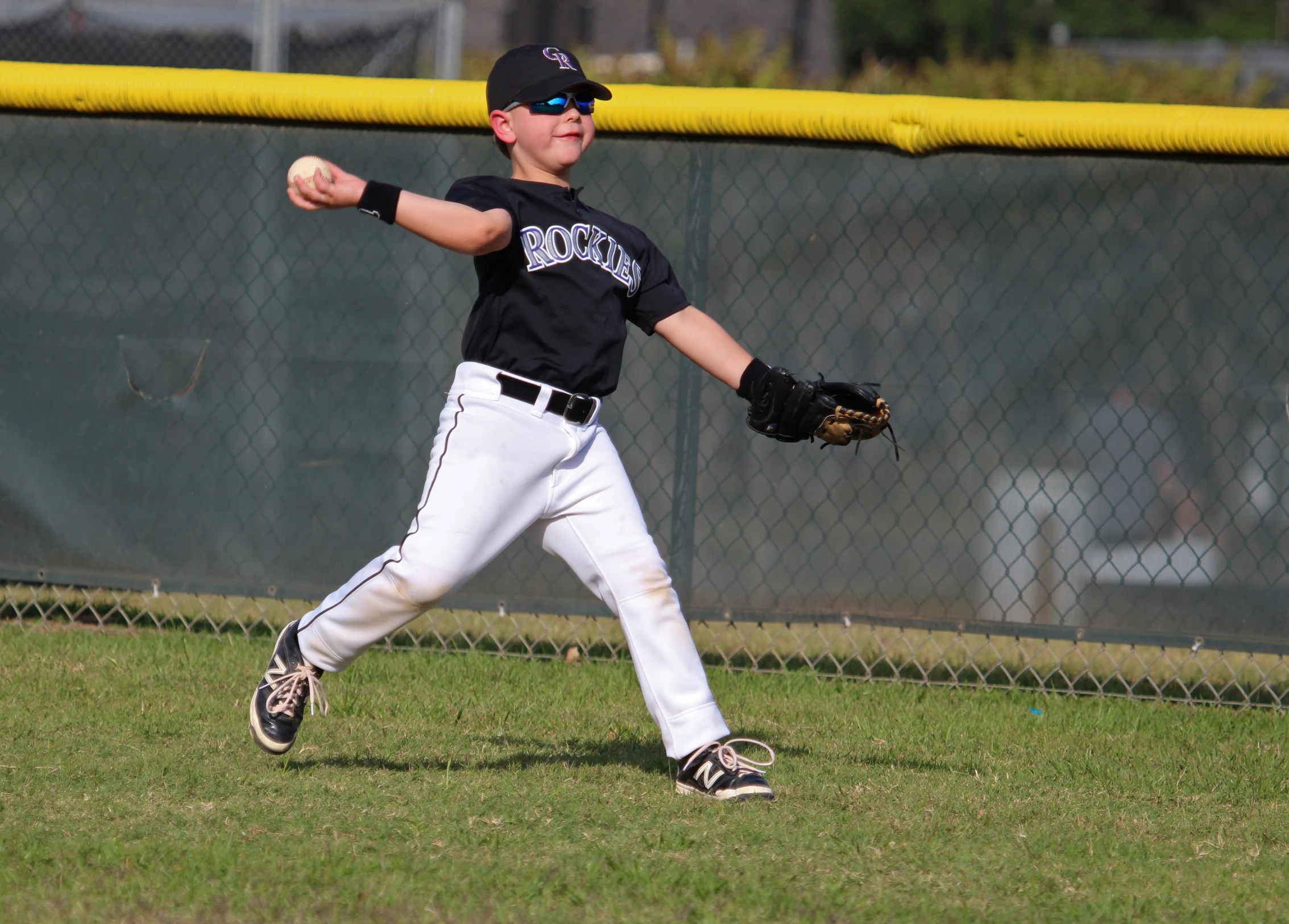  throwing baseball, wearing all black with hat on