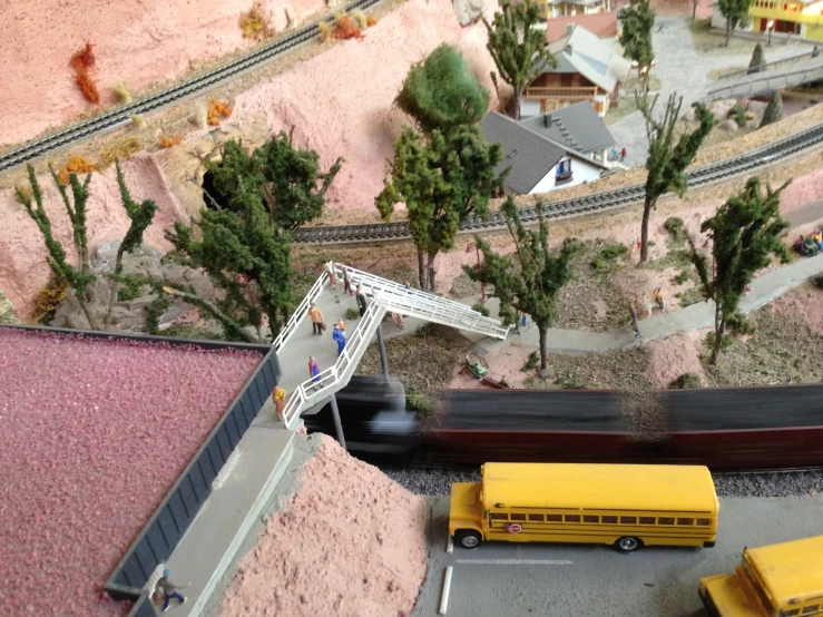 a model train set with a yellow bus and people at it