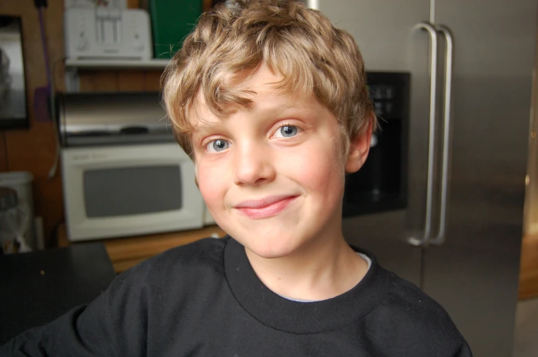 a boy is smiling in front of a refrigerator