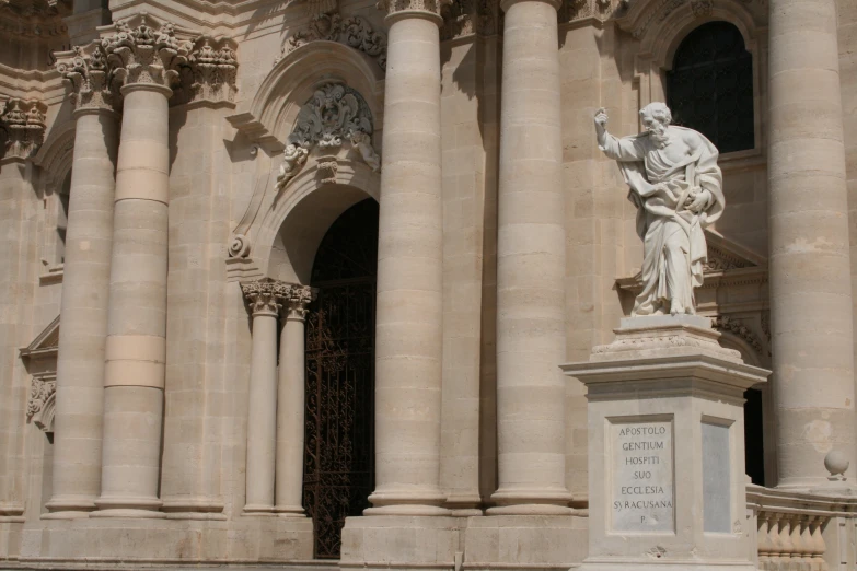 the statue in front of the large building is holding a book