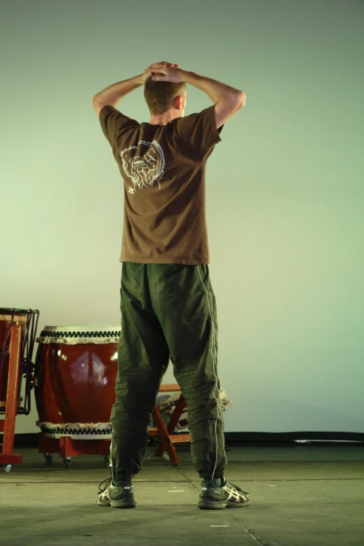 a man in a room standing behind some drums