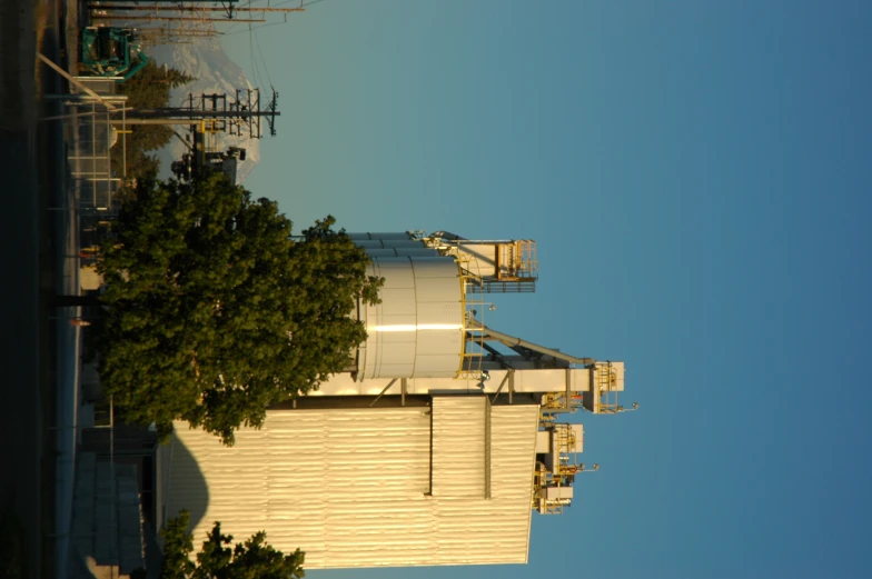 a large cement factory building next to a green tree