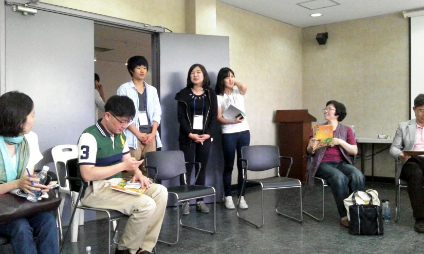 several people sitting around talking and holding books