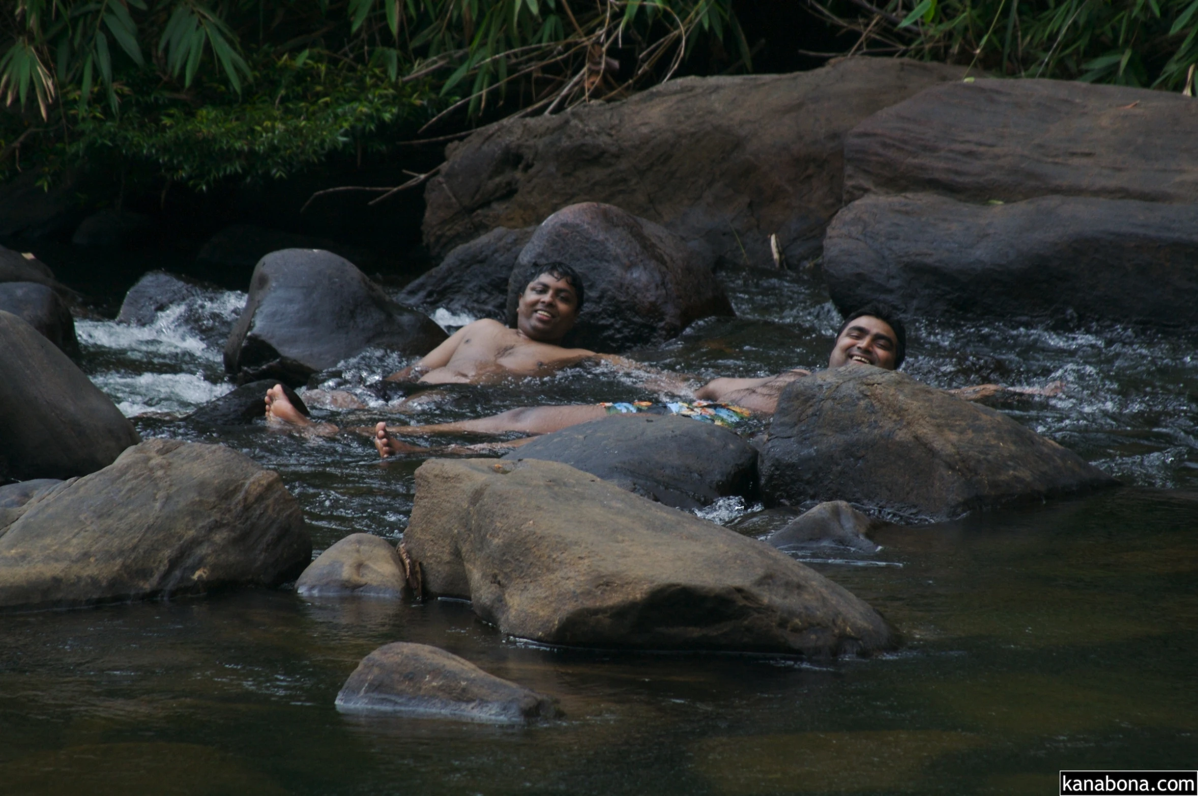 some people are in the water on big rocks