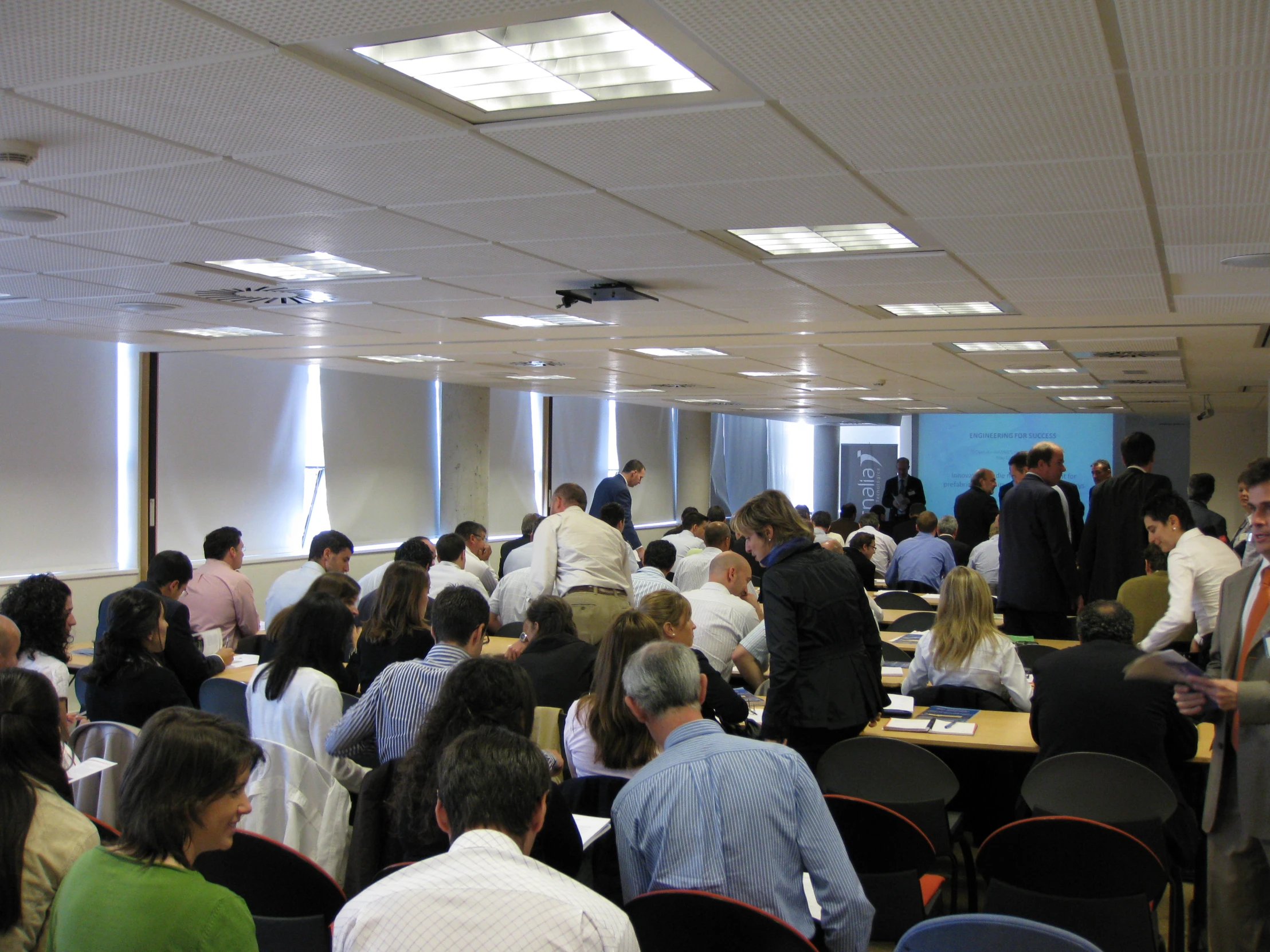 many people are gathered at tables to listen to a speaker