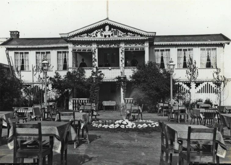 an old po of a building that has tables and chairs