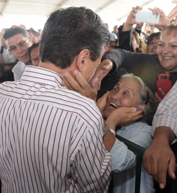 an old man in a red and white shirt surrounded by people