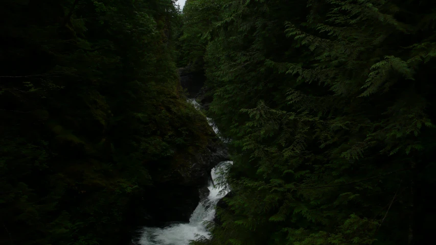 a large waterfall running over lush green trees