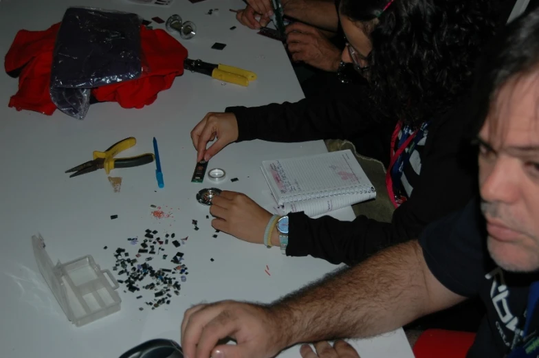 two people working at a table covered with beads