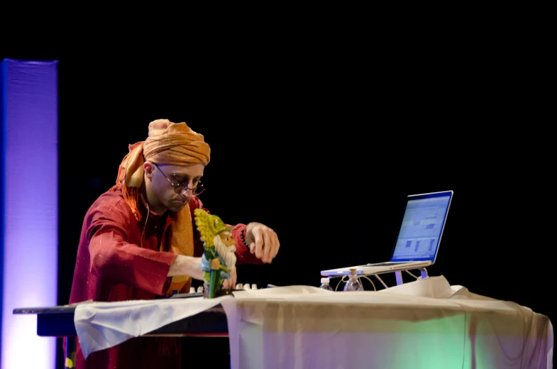 a man wearing a turban is on his laptop at a table