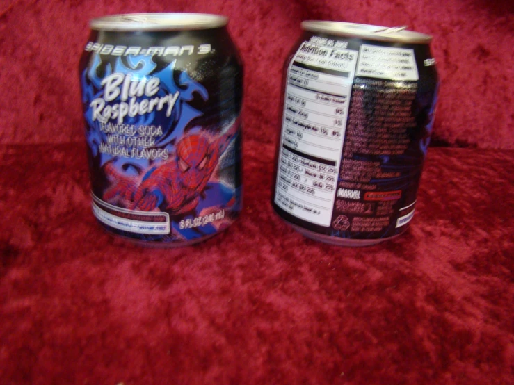 two cans are side by side on a red blanket