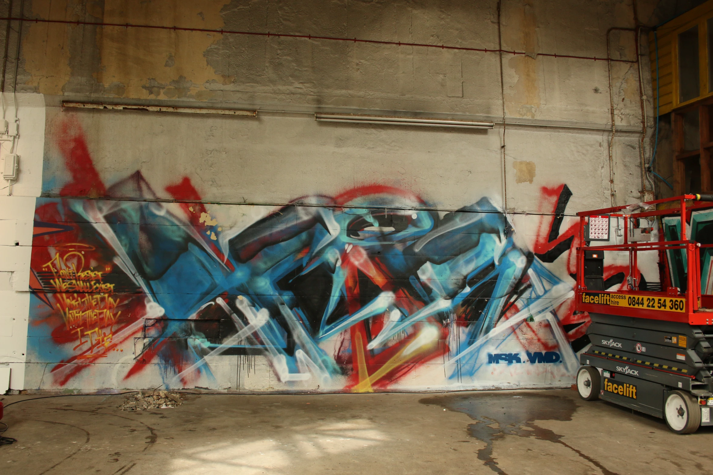 a fire truck and some graffiti are parked in front of a large wall