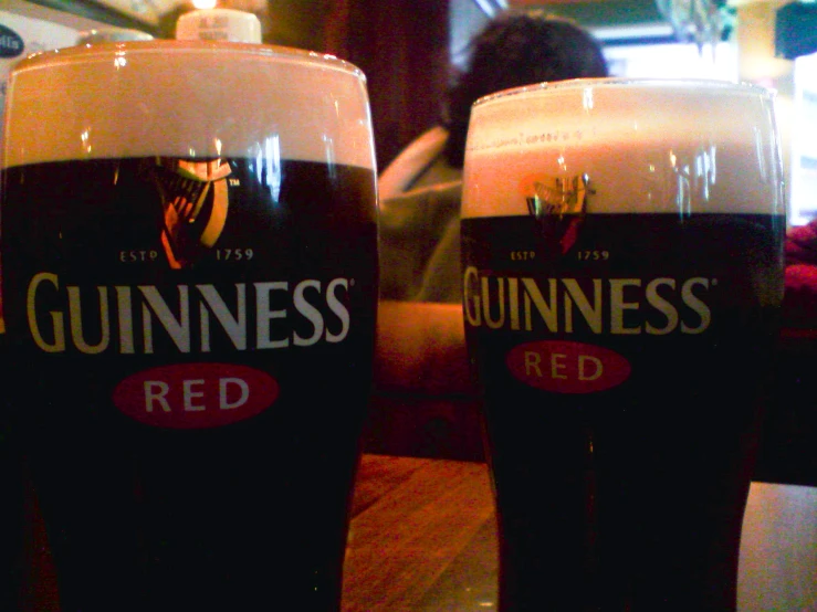 two glasses of guinness sitting on top of a table
